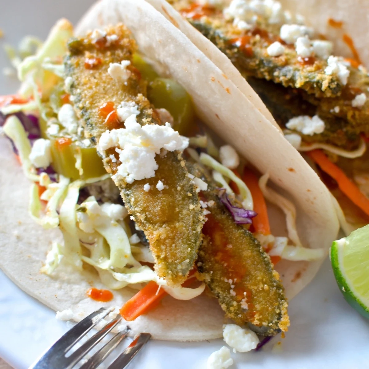 Crispy Sweet Chili Fried Pickle Tacos with tangy slaw and vibrant lime wedges.  