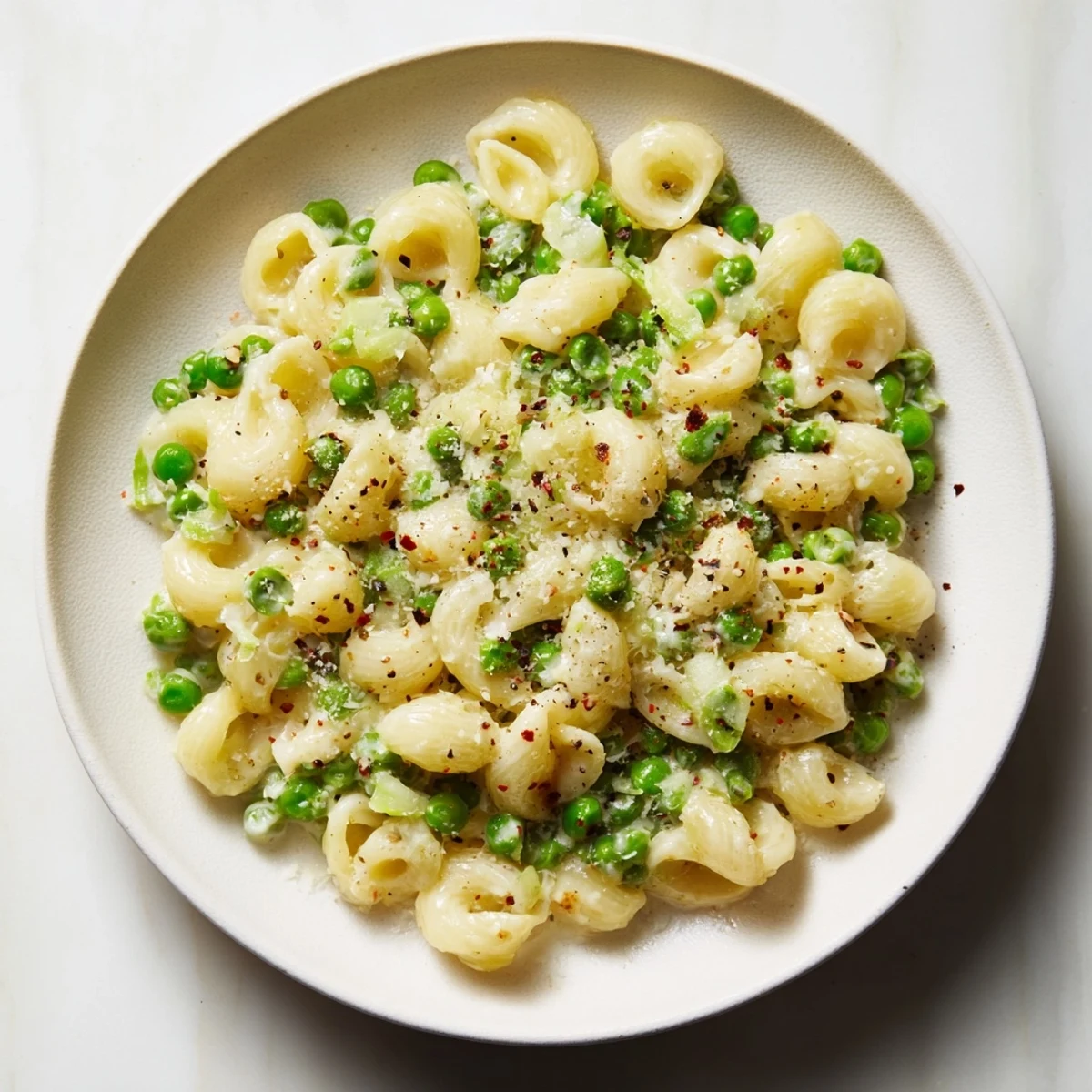 Close-up of golden Macaroni & Peas, tossed with peas and Parmesan cheese.
