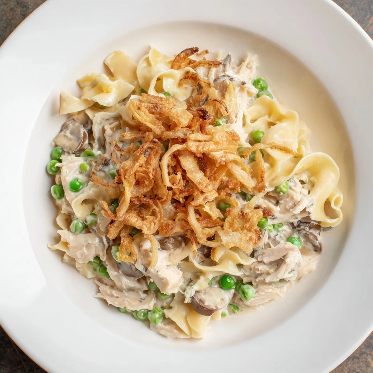 A bubbly pan of Creamy Tuna Noodle Casserole topped with crispy, golden brown fried onions.