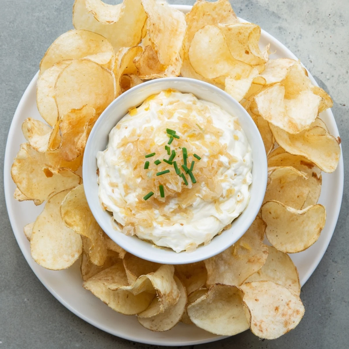 Crispy potato chips alongside creamy onion dip, an ideal snack for your favorite gathering.