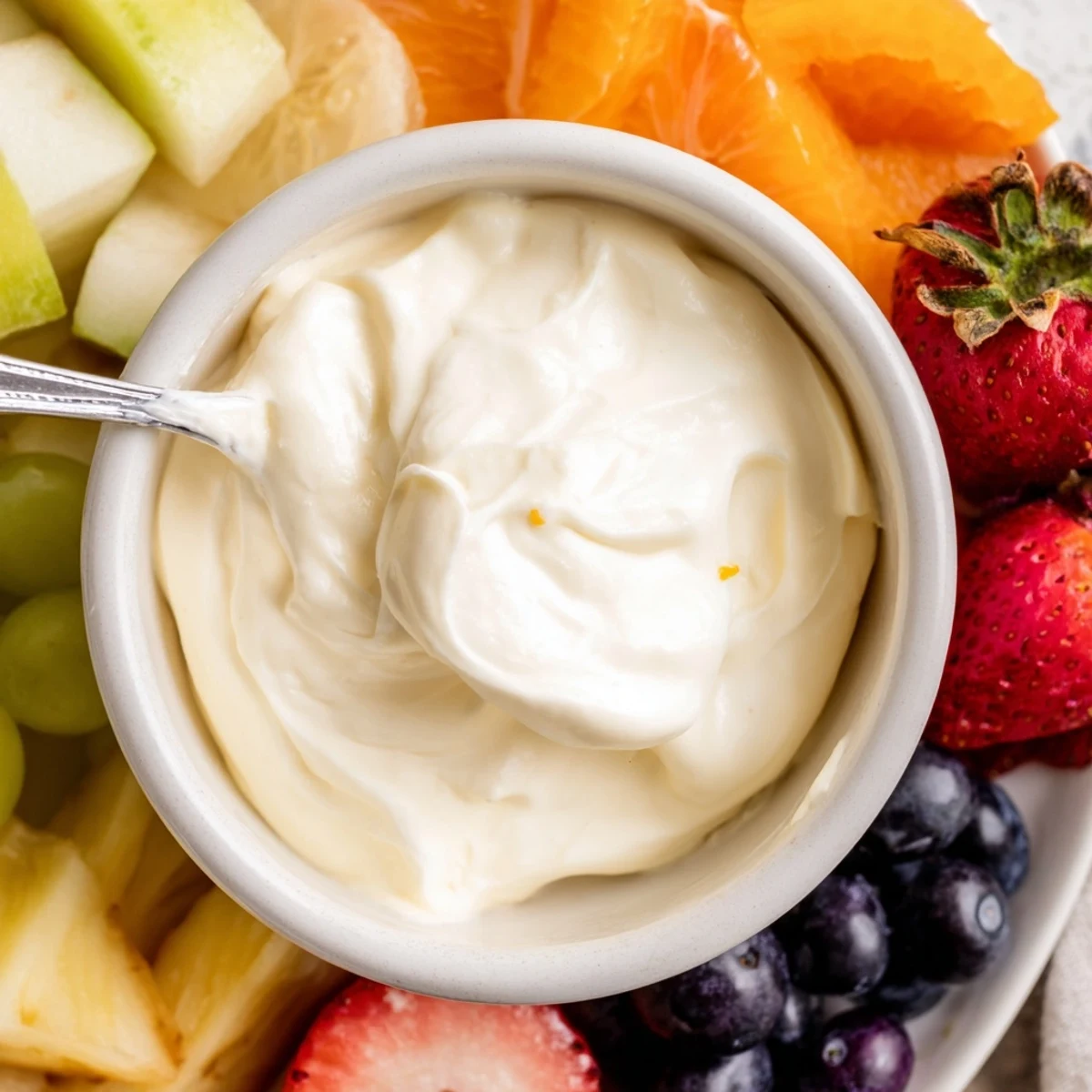 Creamy cream cheese fruit dip in a bowl surrounded by colorful, inviting fresh fruit.