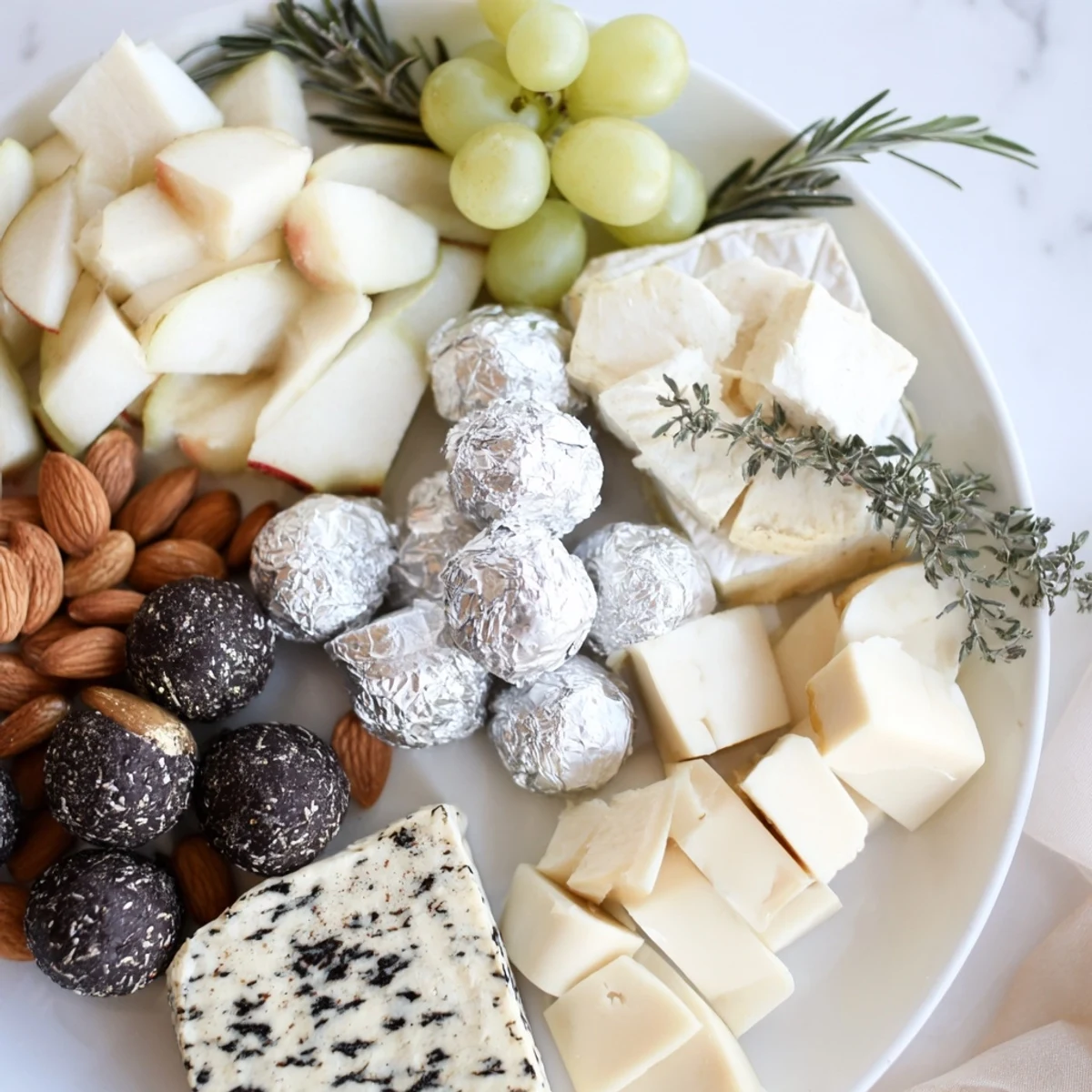 Elegant The Silver Screen cheese board, a monochromatic appetizer with truffle cheeses, silver chocolates, and grapes.