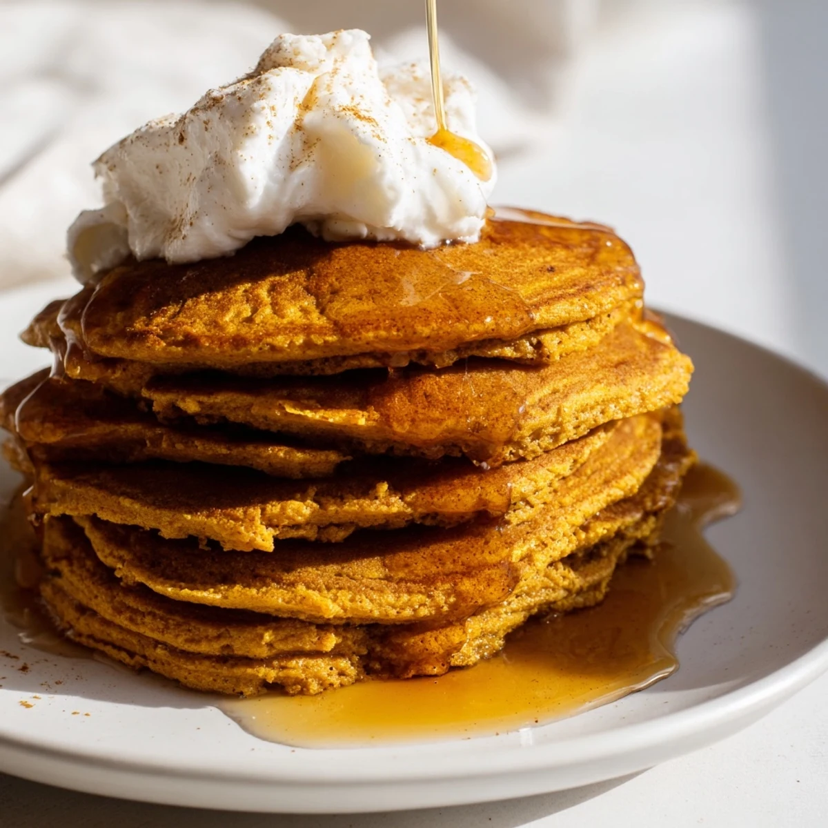 Golden-brown and fluffy pumpkin spice pancakes, piled high, ready to be drizzled with syrup.