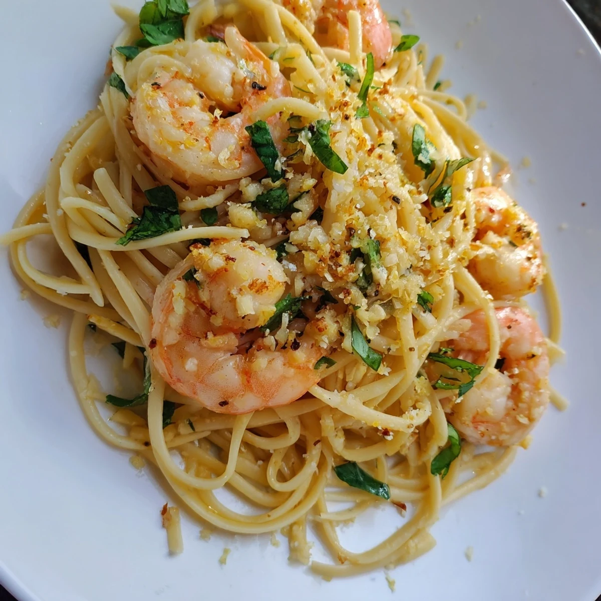 Steaming plate of lemon herb pasta with shrimp, garnished, ready to enjoy this delightful meal.