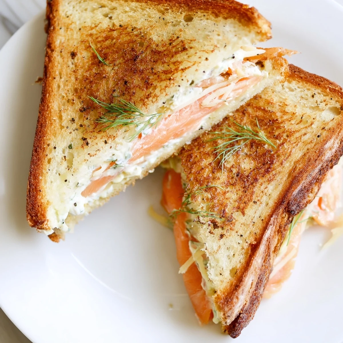 Golden-brown Smoked Salmon Grilled Cheese sandwich, cheese oozing, served with fresh dill, ready to eat.