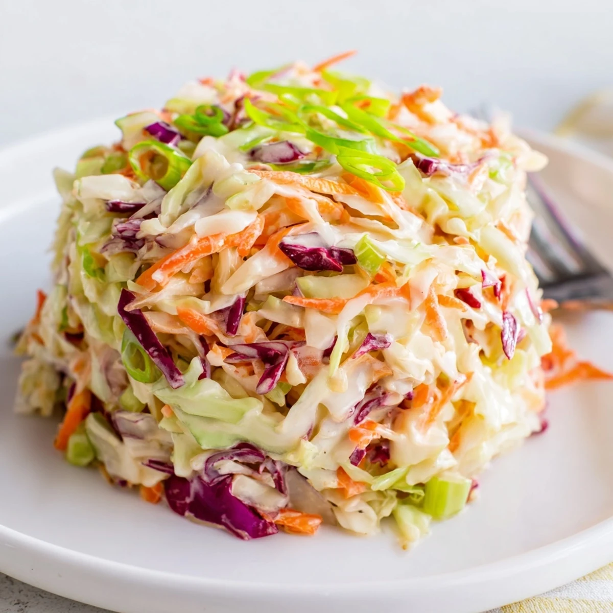 This easy vegetarian coleslaw recipe showcases finely chopped cabbage and carrots tossed in a smooth dressing, perfect for a refreshing summer picnic side dish.
