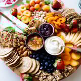 Colorful combination of creamy cheeses and sweet jams on a rustic wooden platter.  