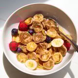 Fluffy mini pancakes served in a bowl, drizzled with honey and milk.  