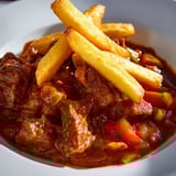 A steaming bowl of Czech Goulash Potato, boasting flavors of beef and spices with fried potatoes.