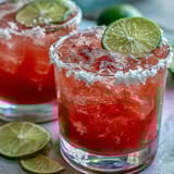 Two glasses of vibrant pink Best Guava Margarita, filled with ice and fresh fruit garnish.