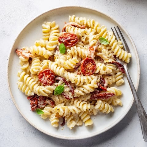 Creamy Baked Feta Pasta topped with caramelized onions and sun-dried tomatoes.  