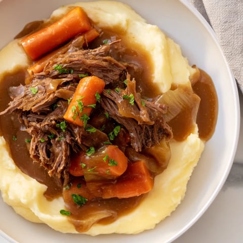 Tender Slow Cooker Pot Roast with mashed potatoes, offering a hearty, home-cooked American meal.