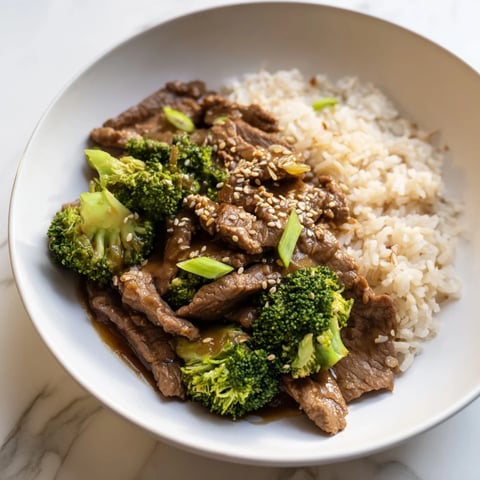 Tender Slow-Cooker Beef & Broccoli with a rich sauce, served with fluffy brown rice and fresh greens.
