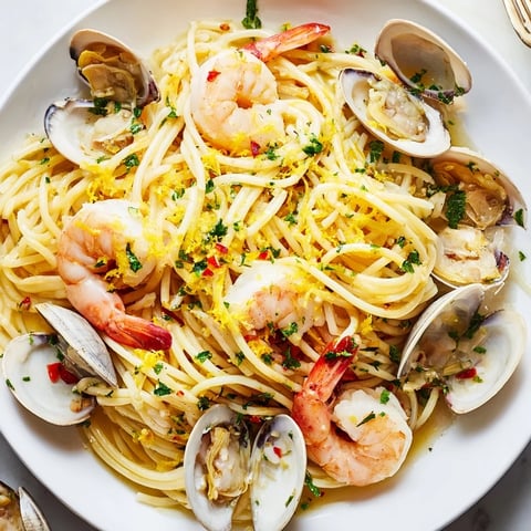 Steaming Seafood Pasta Aglio e Olio with plump shrimp and clams, ready to be served.