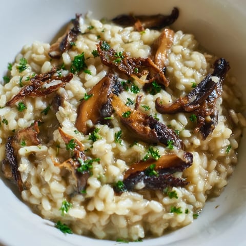 Creamy Roasted Mushroom Risotto in a white bowl, garnished with fresh parsley and extra Parmesan, ready to serve as a comforting main dish.