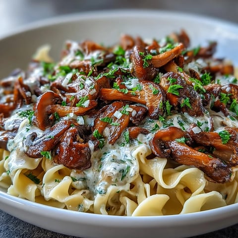 Creamy Mushroom Stroganoff served in a bowl with wide noodles and chopped parsley garnish