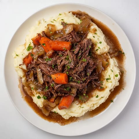 Fork-tender Slow Cooker Pot Roast with vibrant vegetables, swimming in rich gravy, and creamy mashed potatoes.