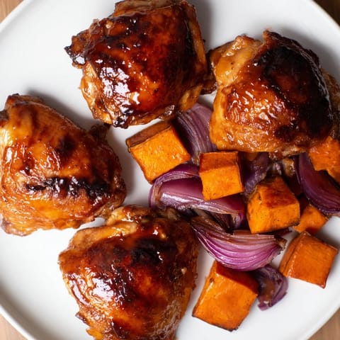 A close-up shot of Maple Glazed Chicken & Sweet Potato Bake, glistening with a rich maple syrup glaze.