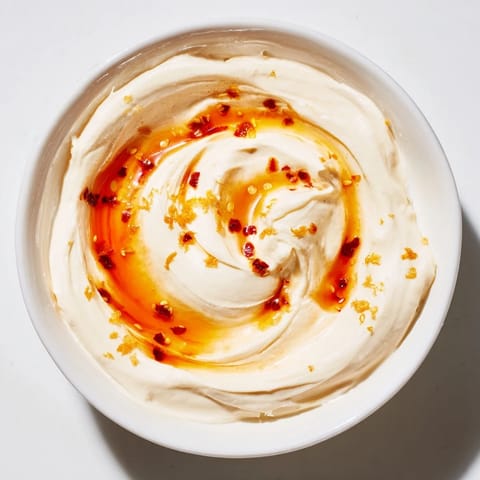 Close-up of fluffy whipped ricotta dip, drizzled with spicy hot honey, inviting a delicious taste.