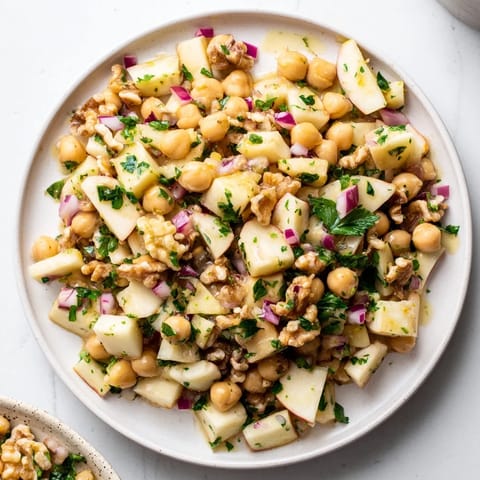 Freshly tossed Fall Harvest Apple and Chickpea Salad showing diced apples, walnuts, and a tangy dressing.