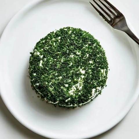 Fresh parsley and dill coat goat cheese rounds, mimicking mossy stones for a whimsical "Mossy Stones" appetizer.