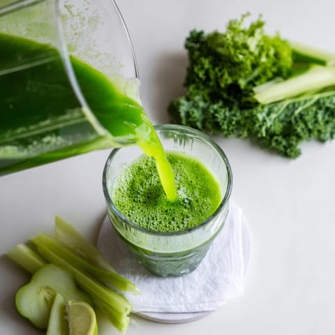 Two servings of Cabbage and Kale Detox Juice in clear glasses, showing the vibrant green color and a frothy top.