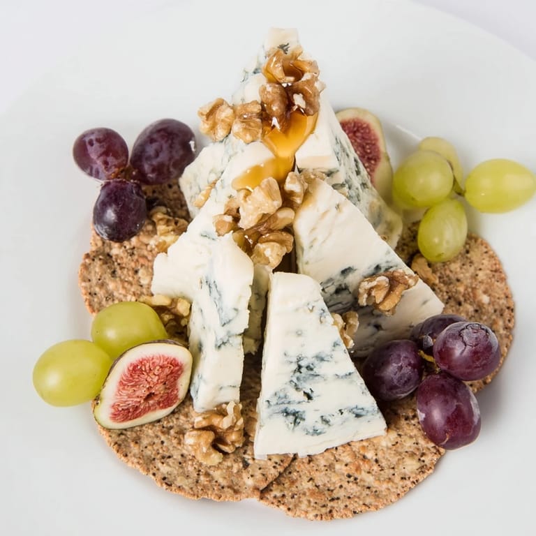An elegant appetizer featuring a Blue Ridge Mountains cheese platter: blue cheeses, crackers, and garnish for serving.