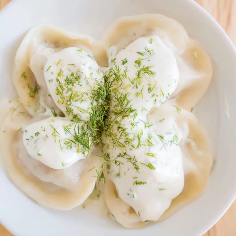 Steaming plate of savory Russian pelmeni, garnished with fresh dill and served hot for dinner.
