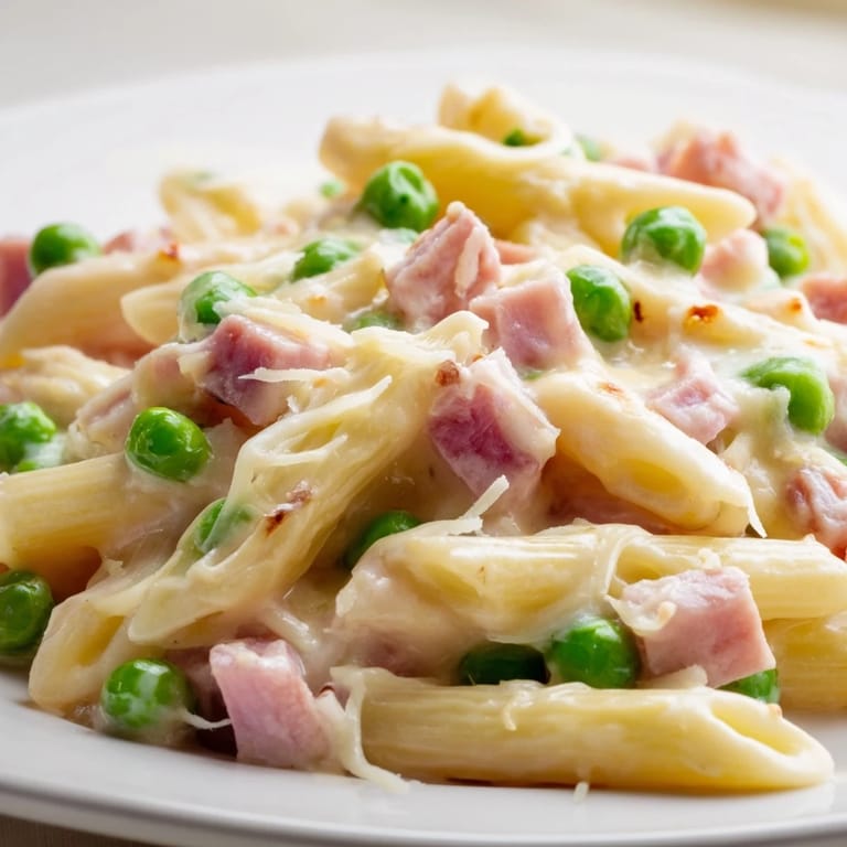 Spring Pea & Ham Pasta served warm in a white bowl, garnished with fresh parsley and extra Parmesan for a hearty meal.